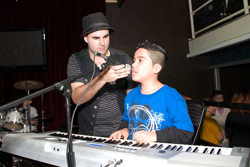 Piano instructor adjusting the student's mic on stage